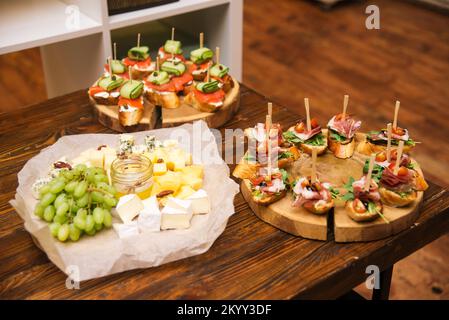 une table de hors-d'œuvre de fête froide. un ensemble de tranches de fromage avec du raisin et du fromage, deux planches de tapas de fromage cottage avec filet de saumon et concombre, un Banque D'Images