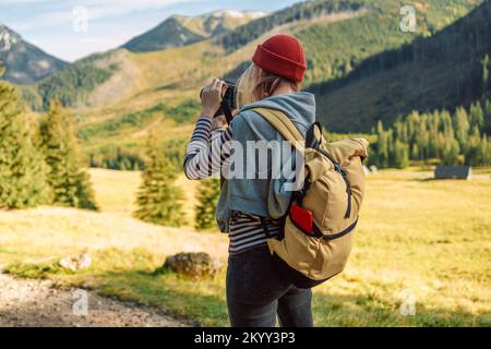 Jeune femme caucasienne avec sac à dos jaune prenant une photo sur le sommet des montagnes. Tatras, Pologne Banque D'Images