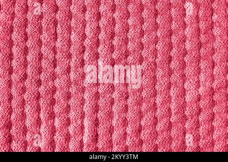 La texture du tissu tricoté. Gros plan d'une couverture tricotée. Démonstration des couleurs de 2023 - Viva Magenta. Banque D'Images