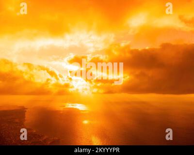 Vue aérienne coucher de soleil rouge sur la mer avec falaise volcanique rocheuse. Résumé nature été coucher de soleil océan mer fond. Petites vagues sur doré chaud Banque D'Images