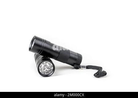 Deux lampes de poche à LED noires reposant l'une sur l'autre sur un arrière-plan blanc Banque D'Images
