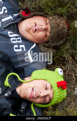 Tous partiés. Un homme en surpoids et son copain couchés sont passés sur l'herbe avec leurs langues accrochée. Banque D'Images