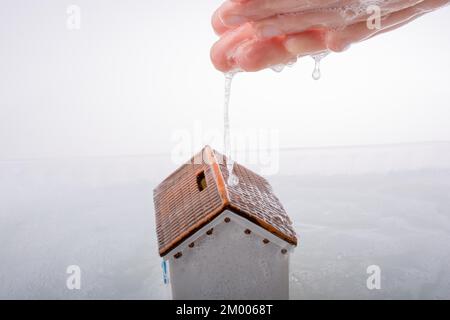Main tenant une maison modèle dans l'eau mousseuse Banque D'Images