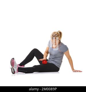 Déploiement de ses cuisses intérieures. Une jeune femme utilisant une balle d'exercice pour s'entraîner. Banque D'Images