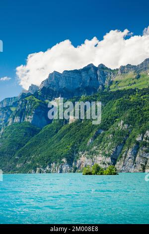 Vue ensoleillée sur le lac Walen avec la petite île de ciboulette dans l'eau turquoise et la chaîne de montagnes Schären et Leistchamm en arrière-plan, Canton St. Banque D'Images