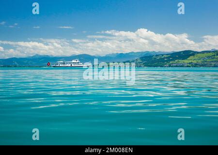Bateau de cours avec drapeau suisse sur les eaux turquoises du lac de Constance en face des Alpes autrichiennes Banque D'Images