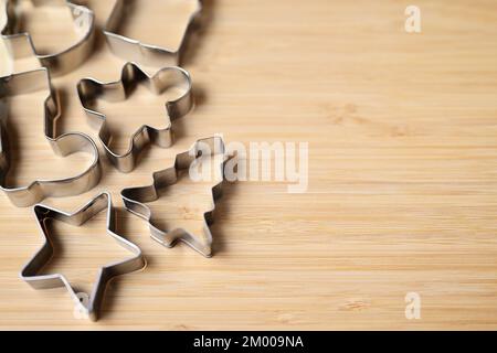Emporte-pièces en métal de différentes formes pour biscuits faits maison et pain d'épice sur un fond en bois. Banque D'Images