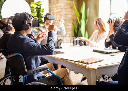 professionnels utilisant un casque de réalité augmentée pour une réunion virtuelle, jeunes hommes d'affaires africains sur des documents défilés en fauteuil roulant et trouver des informations Banque D'Images