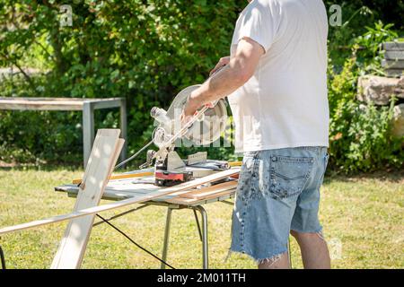 Image de l'homme en utilisant le cercle scie à l'extérieur de couper le bois pour le bricolage maison projet de passe-temps Banque D'Images