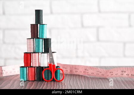 Fils tailleur de couleur pastel empilés en forme de pyramide avec des ciseaux et du ruban adhésif. Arrière-plans à motif brodé Banque D'Images