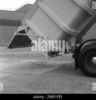 1950s, historique, à l'extérieur d'une aciérie, la photo montre un nouveau camion à benne basculante avec une remorque ou un plateau à caisse ouverte et une porte arrière à charnières ouverte. Cela permet au matériau de la remorque de se déposer, c'est-à-dire de se dévider ou de basculer sur le sol derrière le chariot. Utilisé dans la construction et les industries lourdes, pour le transport de matériaux, cette forme de transport est également connue sous le nom de camion-benne. Banque D'Images