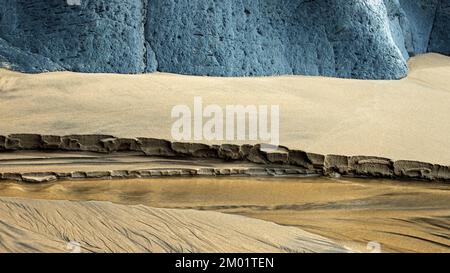 Photographie réaliste et abstraite en couleur des roches côtières et de la plage de sable sculptée par les passages du temps et de la marée avec des motifs et des textures grainés Banque D'Images