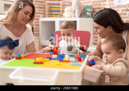 Enseignants et élèves d'âge préscolaire jouant avec des blocs de construction assis sur une table à la maternelle Banque D'Images