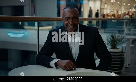 Homme d'affaires d'âge moyen adulte africain visiteur client homme venir dans le café marchant dans la cafétéria assis à table demander à la serveuse appelant serveur appeler le barista Banque D'Images