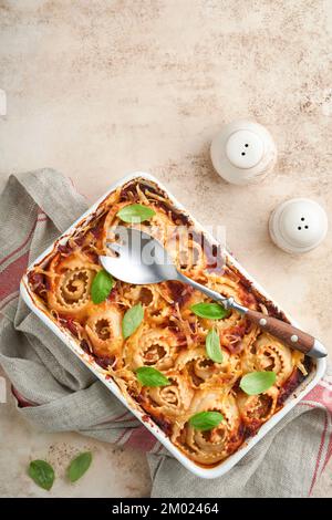 Lasagnes. Pâtes de lasagne faites maison rotolo cuire avec sauce tomate, fromage à la crème et basilic sur une poêle blanche sur fond d'ardoise légère, de pierre ou de béton. JE Banque D'Images