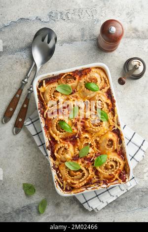 Lasagnes. Pâtes de lasagne faites maison rotolo cuire avec sauce tomate, fromage à la crème et basilic sur une poêle blanche sur fond d'ardoise légère, de pierre ou de béton. JE Banque D'Images