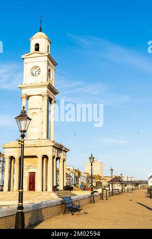 La promenade déserte et la tour de l'horloge sur le front de mer de Herne Bay dans le Kent, à 6 h le matin de l'été, avec un éclairage de l'heure d'or contre un ciel bleu. Banque D'Images