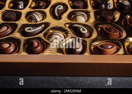 Une boîte de chocolats différents. Assortiment de chocolat sur la table noire, vue du dessus Banque D'Images