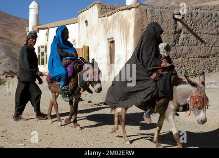 Syadara (Siyah Darah), province de Bamyan (Bamiyan) / Afghanistan: L'homme afghan marche derrière deux femmes à cheval sur des ânes dans la ville de Syadara, en Afghanistan. Banque D'Images