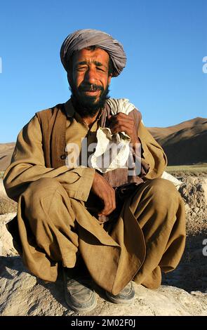 Dowlat Yar, province de Ghor / Afghanistan: Portrait d'un homme avec une barbe noire broussaillée qui s'écrase dans un champ près de Dowlatyar en Afghanistan central. Banque D'Images