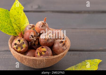 Fruits mûrs en médlar sur une table en bois sombre rustique avec espace pour les copies Banque D'Images