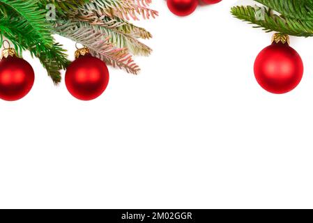 Une branche d'épicéa décorée de rouge boule de Prorhristmas isolée sur fond blanc. Banque D'Images