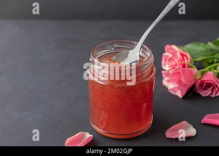 Confiture de pétales de rose bulgare dans un pot avec une cuillère sur fond noir avec espace de copie Banque D'Images