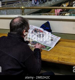 Homme lisant un journal tout en mangeant un bol de soupe au marché intérieur de Cardiff. Photo claire de l'article sur PM Sunak. Banque D'Images