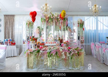 Un grand gâteau sur la table de la mariée. La table de mariage de la mariée et du marié est décorée avec beaucoup de fleurs différentes Banque D'Images