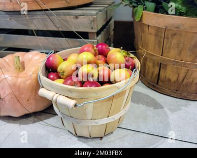 Pommes d'automne dans un panier de boisseaux de bois avec potiron Banque D'Images