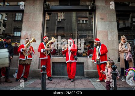 Photo d'un groupe de roms jouant de la musique et chantant pour préparer leur représentation pour un noël dans les rues de Belgrade, vêtu du Père noël. Banque D'Images