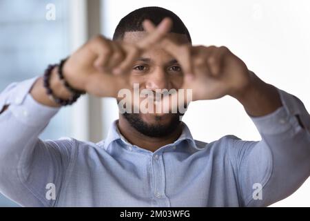 Joyeux jeune homme africain regardant à travers le cadre de photographie de doigt Banque D'Images