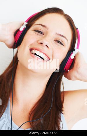 Froid dans la musique. Jolie jeune femme qui écoute de la musique sur son casque tout en étant isolée sur le blanc. Banque D'Images