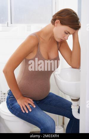 Les épreuves de devenir mère. Une femme enceinte aux prises avec la maladie du matin dans la salle de bains. Banque D'Images