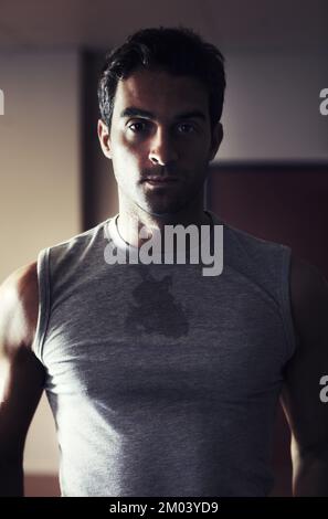 Portrait de la perfection masculine. Portrait d'un homme coiffeur qui porte des vêtements de sport et qui se tient dans un éclairage tamisé. Banque D'Images