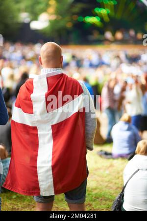 Ventilateur patriotique. Vue arrière d'un homme portant un drapeau danois lors d'un festival de musique en plein air. Banque D'Images