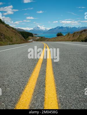 Mt Cook Road avec deux lignes jaunes au milieu, le Mont Cook enneigé au loin, South Island. Format vertical. Banque D'Images