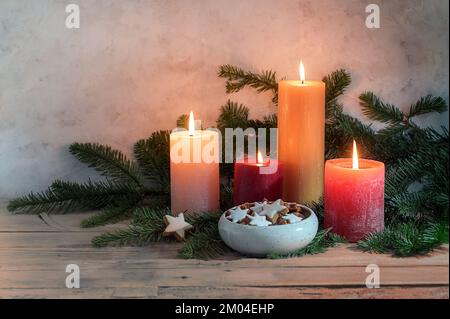 Bougies dans des étoiles d'orange rouge et de cannelle dans un bol sur des branches de sapin, arrangement décoratif pour l'Avent et l'heure de Noël sur une table rustique en bois, cop Banque D'Images