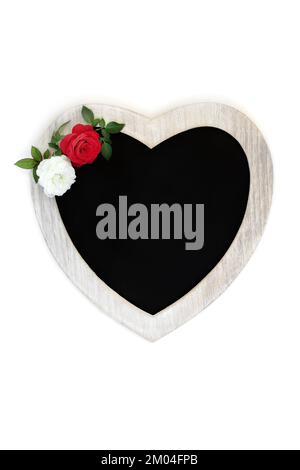 Symbole d'amour et de romance de la Saint-Valentin avec cadre en bois en forme de coeur, tableau noir, fleurs roses blanches et rouges. Convient pour le jour de la mère ou l'anniversaire Banque D'Images