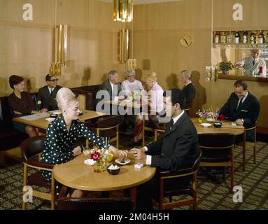 Dans le 1960s. Les gens dans le restaurant de l'hôtel Continental à Stockholm. La femme blonde à la table de devant a ses cheveux dans la coiffure typique de Beehive, dans laquelle ses cheveux longs sont empilés sur le dessus de la tête et donnant une certaine ressemblance à la forme d'une ruche traditionnelle. Suède 1969 Conard réf. BV106-5 Banque D'Images