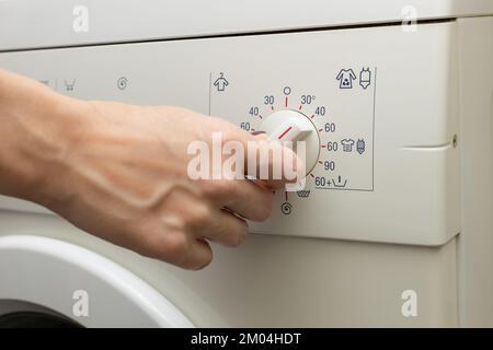 une personne choisit un mode de lavage à l'aide d'un interrupteur. Banque D'Images