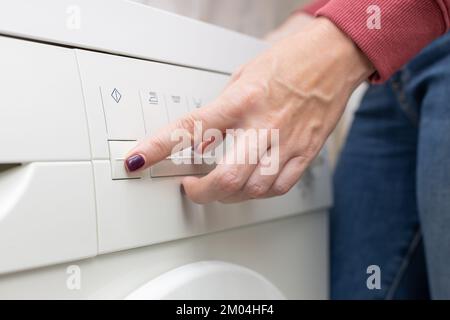 l'homme appuie sur le bouton du lave-linge Banque D'Images