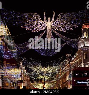 L'esprit de Noël s'affiche sur Regent Street avec les lumières réfléchis sur le côté d'un bus qui passe. Londres. Banque D'Images