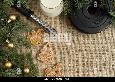 Biscuits de Noël en pain d'épice, assiette de poids de haltères de gym, verre de lait pour le Père Noël. Composition du régime d'hiver de la saison des fêtes avec espace de copie. Banque D'Images