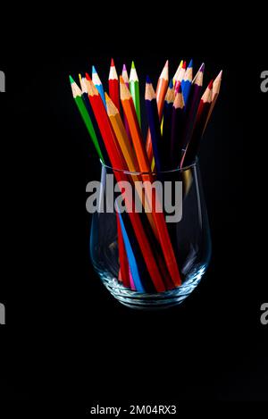 crayons multicolores dans un verre à vin et un seau. Flou sélectif un groupe de crayons de couleur dans un verre de vin sur le dos blanc ou noir isolé Banque D'Images