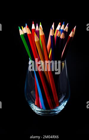 crayons multicolores dans un verre à vin et un seau. Flou sélectif un groupe de crayons de couleur dans un verre de vin sur le dos blanc ou noir isolé Banque D'Images