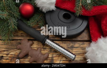 Assiette à haltères, biscuits de Noël au pain d'épice au chocolat, chapeau rouge du Père Noël. Régime de remise en forme d'hiver, entraînement de gym, concept de régime. Banque D'Images