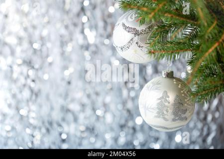 Décorations de Noël. Deux boules de Noël argentées avec dessins sur l'arbre de Noël sur fond de bokeh argenté Banque D'Images