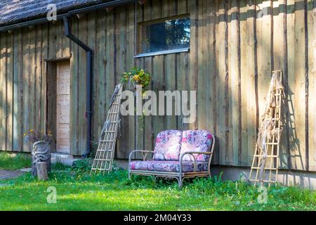 Un canapé rose est placé à côté d'une maison texturée en herbe verte Banque D'Images