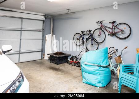 Un garage de deux voitures qui est la plupart du temps vide avec une voiture et des vélos organisés et accrochés au mur Banque D'Images